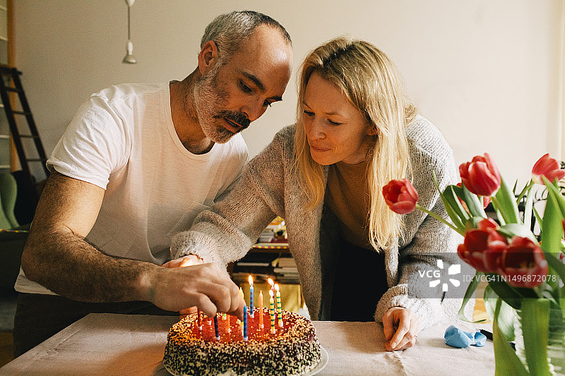 情侣在家一起在生日蛋糕上摆放蜡烛图片素材