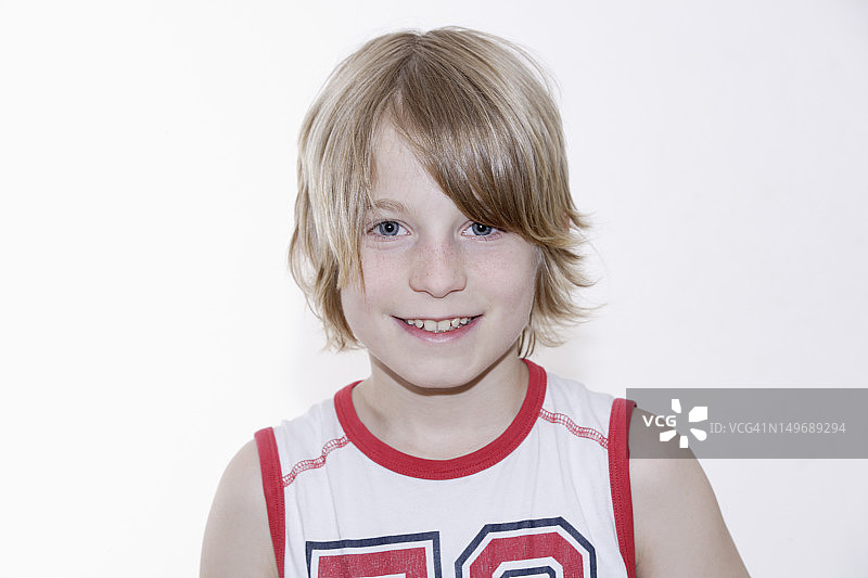 对着白色背景微笑的男孩肖像图片素材