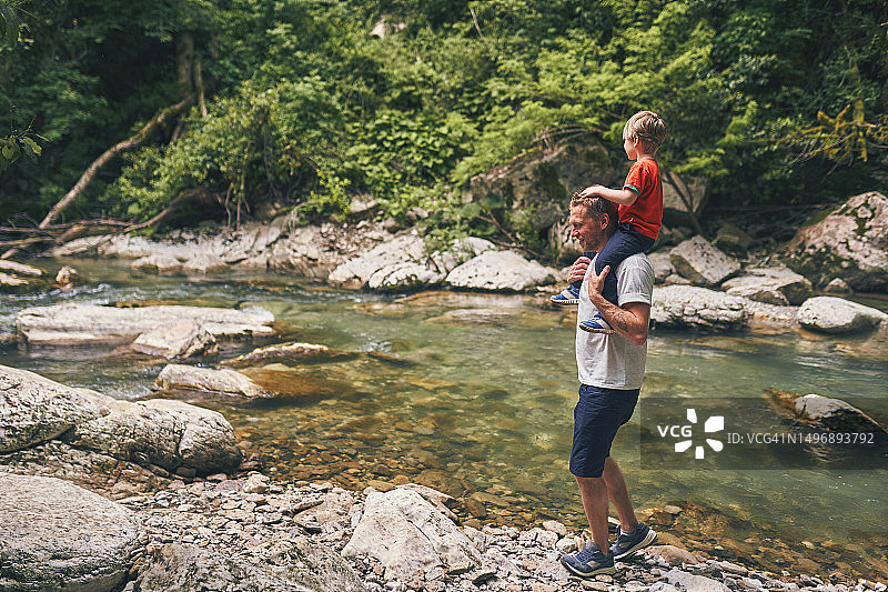 父子沿着山间河流旅行图片素材