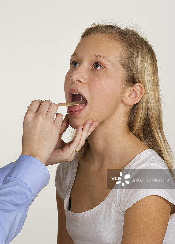 女医生用压舌板检查少女的喉咙图片素材