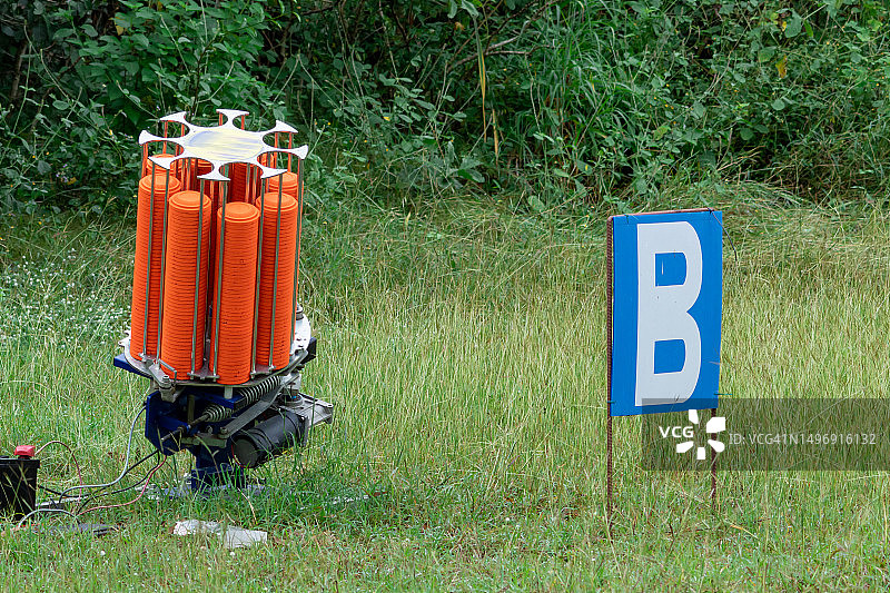 带有橙色射击盘的抛靶机，用于草地上的射击训练图片素材