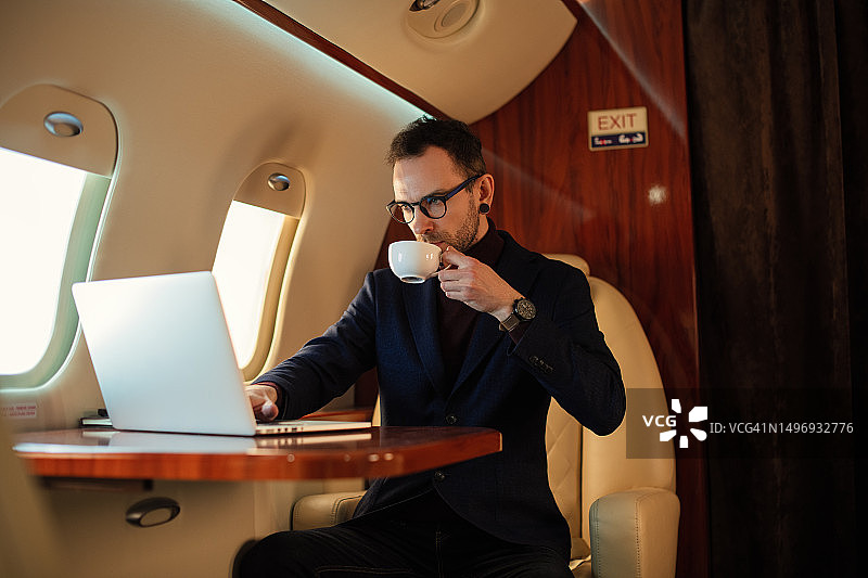 在私人飞机头等舱用笔记本电脑工作的富有男CEO图片素材