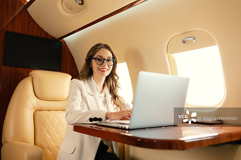 金发女性SEO经理在头等舱私人飞机上用笔记本电脑工作图片素材