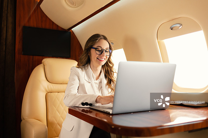 在私人飞机上用笔记本电脑工作的年轻SEO经理图片素材
