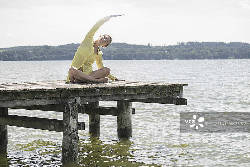 在湖边木板路上做瑜伽的女人图片素材