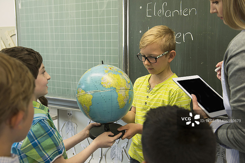 女教师和学生在教室里看地球仪，德国慕尼黑巴伐利亚图片素材