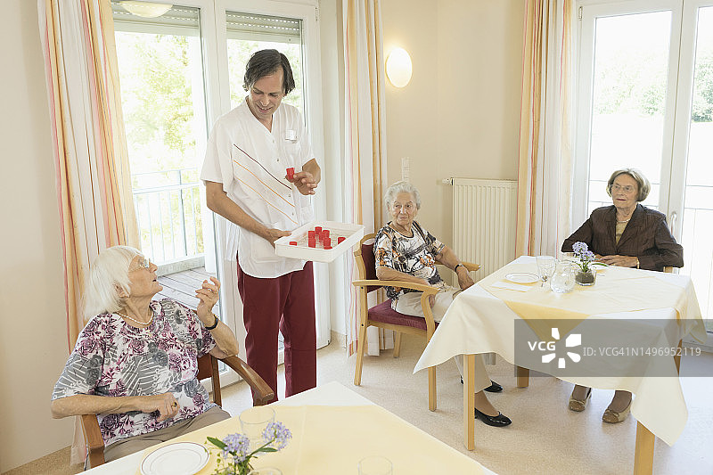 护理人员在养老院给年长女性喂药图片素材