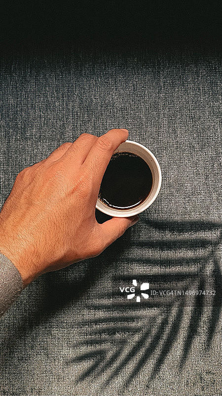 男子在沙特阿拉伯桌上 holding 咖啡杯的手部特写图片素材