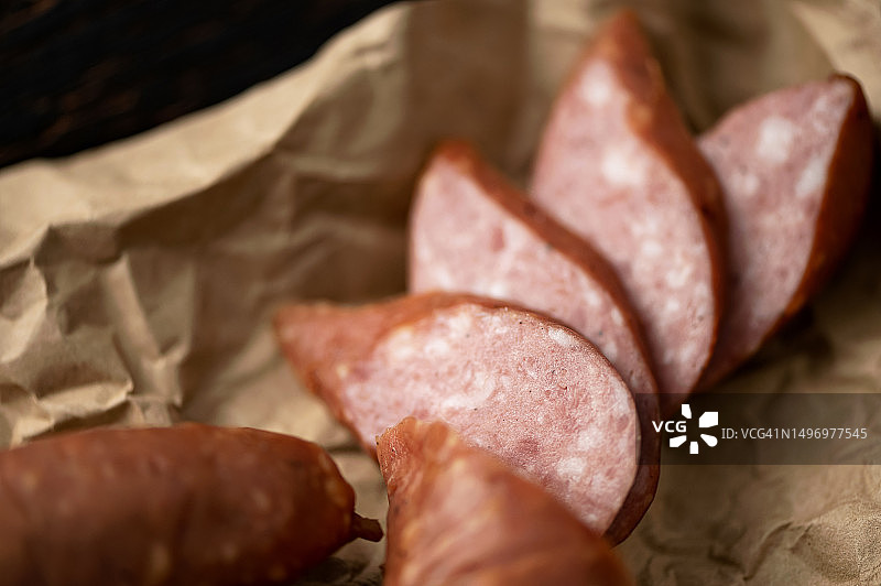 半熏香肠圈，用包装纸包裹的切成圆圈的香肠，克拉科夫香肠片，自制香肠，深色背景，特写，俯视，柔焦图片素材
