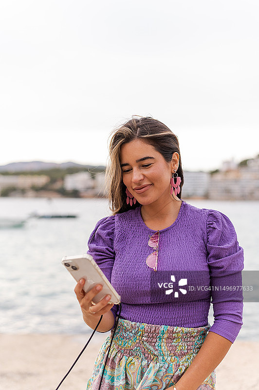 在海边使用手机的优雅女人图片素材