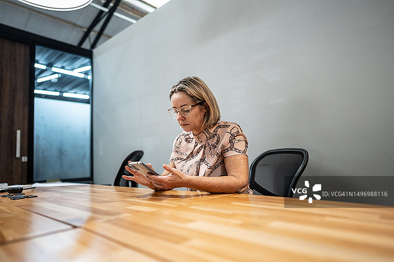 中年妇女在办公室使用手机图片素材