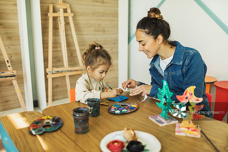 在儿童俱乐部里绘画的可爱女孩和老师图片素材