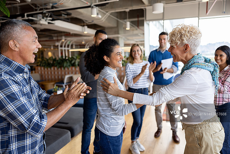 老板在办公室给女性晋升，团队为她鼓掌图片素材
