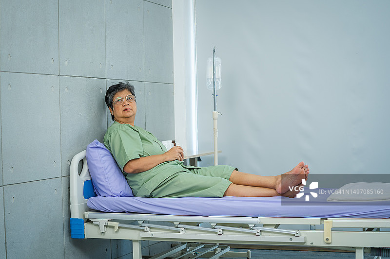在医院里躺在床上、望着窗外的亚洲抑郁老年女病人图片素材