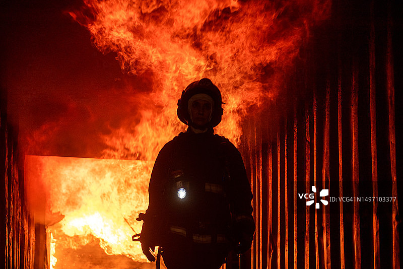 消防员站在大火前的轮廓，火灾保险概念图片素材