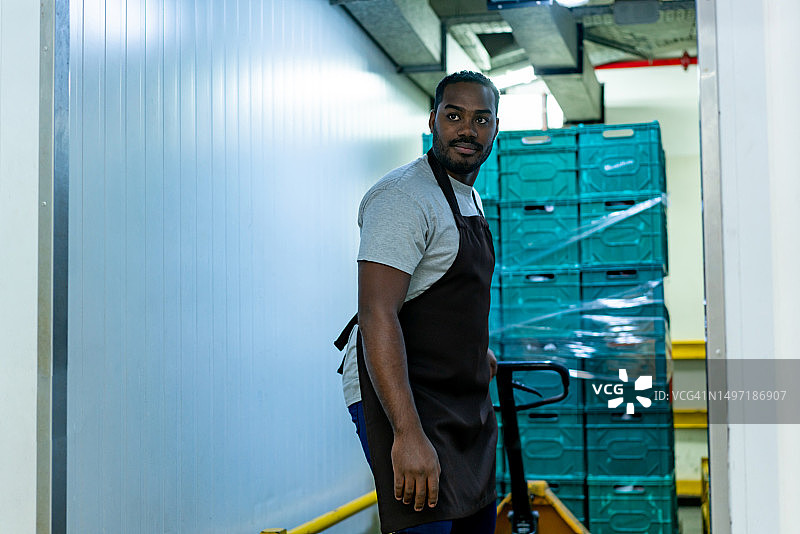 黑色男员工驾驶叉车在超市补充冷冻食品图片素材