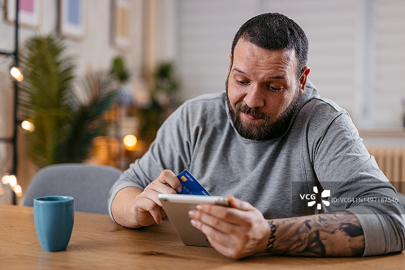 年轻男子手持平板电脑和信用卡进行在线支付图片素材