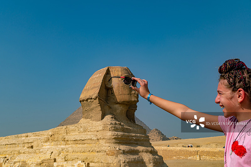 少女给背景中的斯芬克斯戴墨镜图片素材