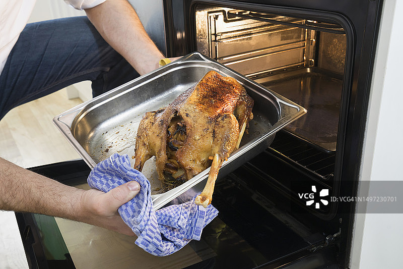 厨师从厨房的烤箱里取出圣诞家禽图片素材