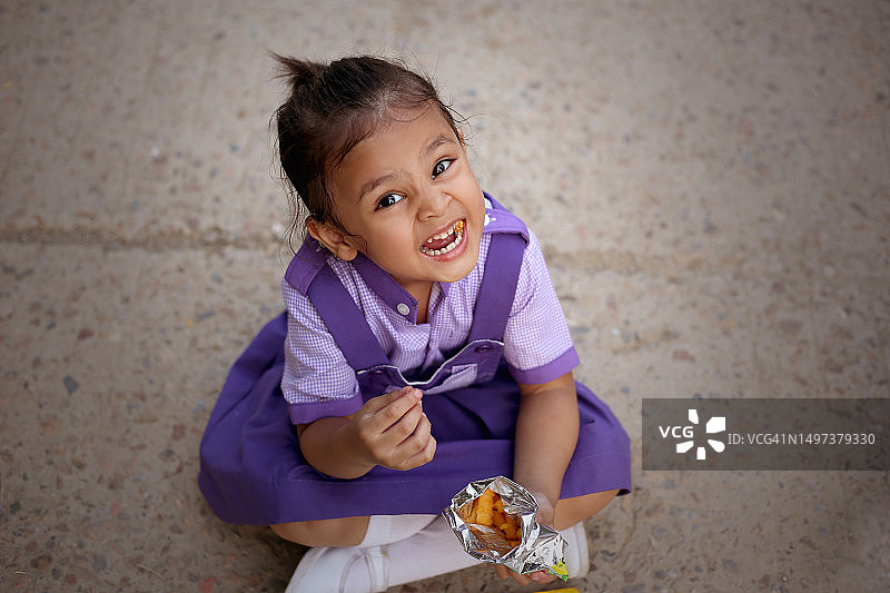 女学生在户外地板上享用零食图片素材