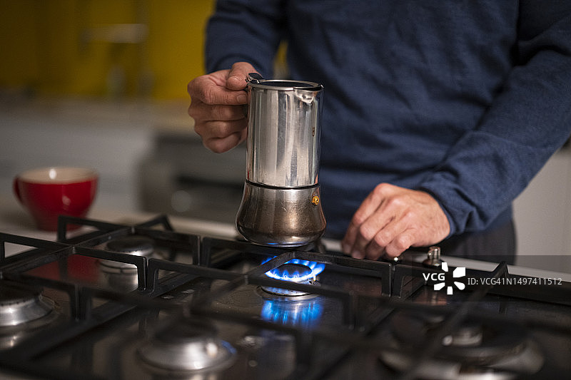 男人点燃煤气灶上的咖啡壶特写图片素材