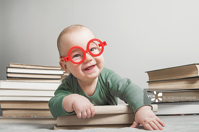戴眼镜看书的五个月大新生儿宝宝特写图片素材
