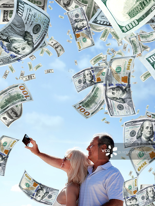 穿着考究的中年白人夫妇在落下的钱雨中合影图片素材