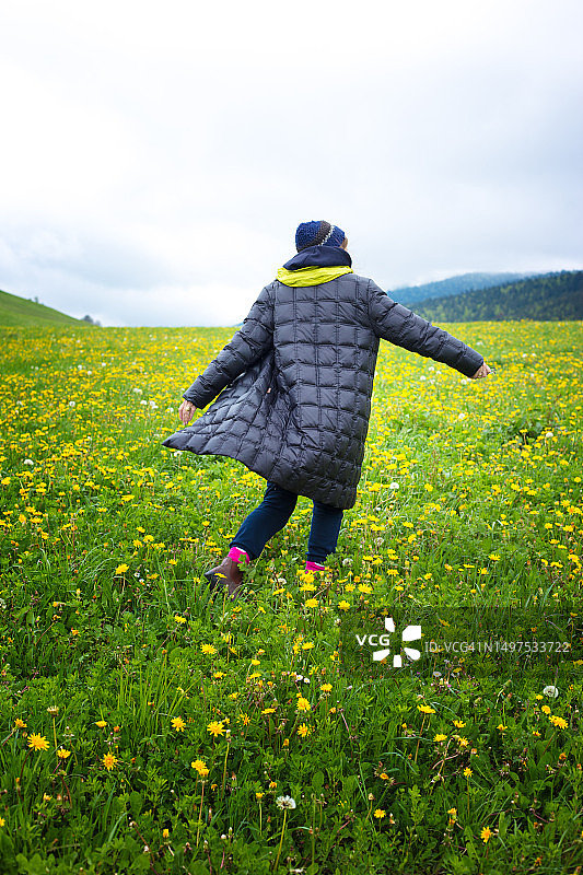 快乐的女人在开满鲜花的草地上跑步/旋转（韦科尔，法国）图片素材