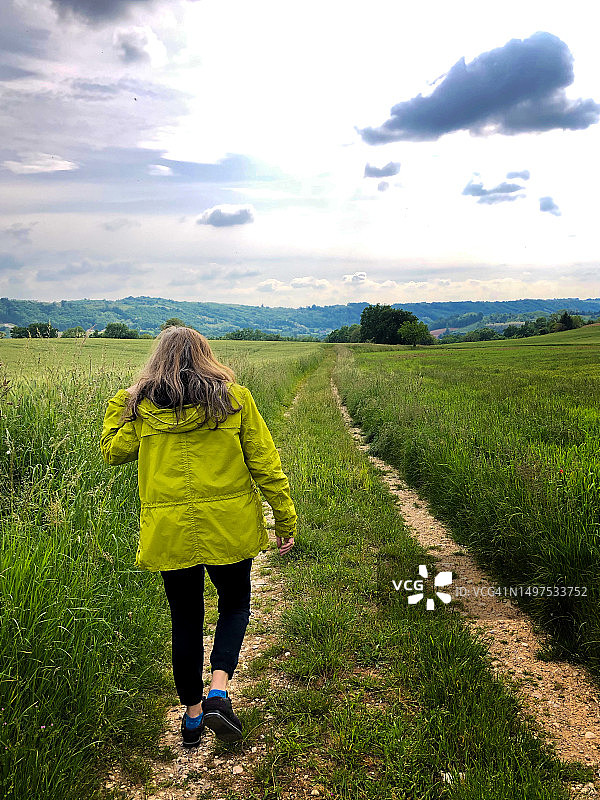 在法国伊泽尔省春天草地上行走的女人图片素材