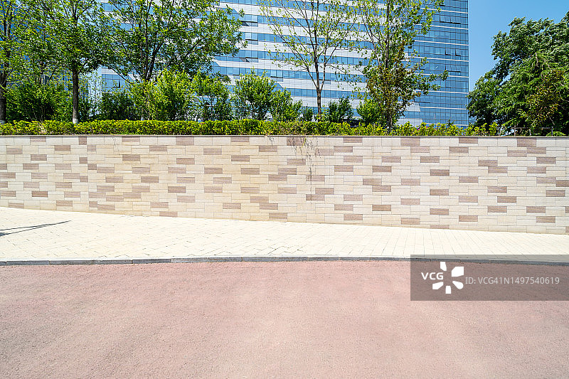 空旷的道路与覆盖绿色植物的背景墙，位于现代办公楼前图片素材
