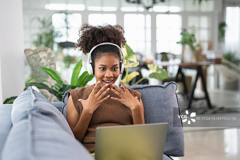 年轻女子戴着耳机在笔记本电脑上看电影图片素材