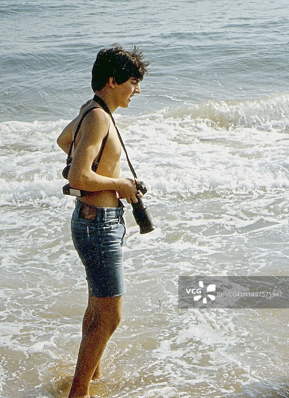 在海边拍照的年轻摄影师图片素材