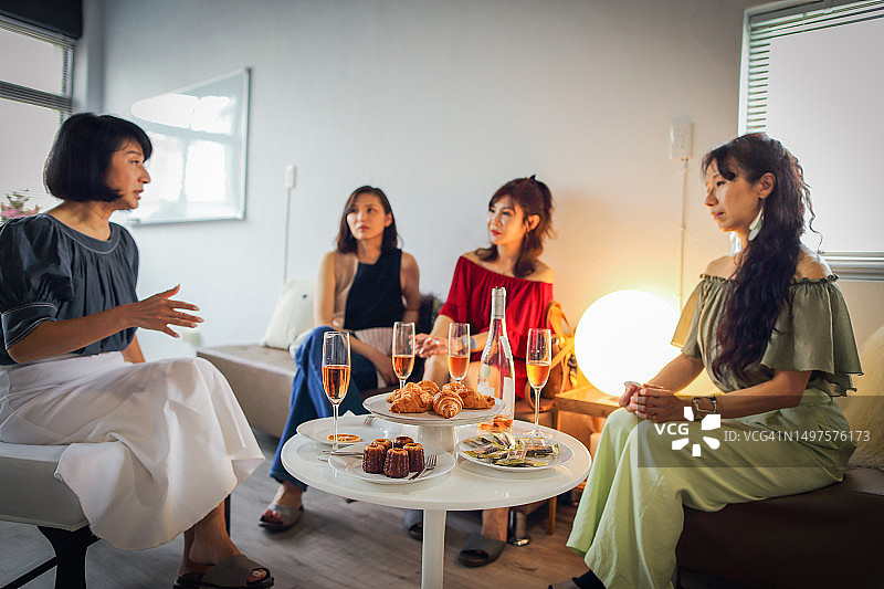 一群妇女在享用下午茶点和白葡萄酒时聊天图片素材