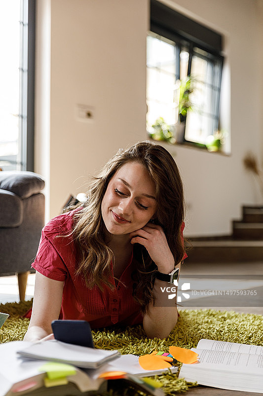 年轻女人在学习之余通过智能手机与朋友进行视频聊天图片素材
