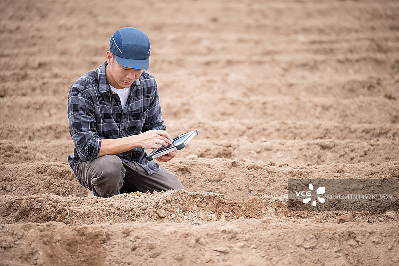 土壤测试有助于优化肥料支出、改善土壤健康，日本农场主使用平板电脑检查田地土壤，为种植做准备图片素材