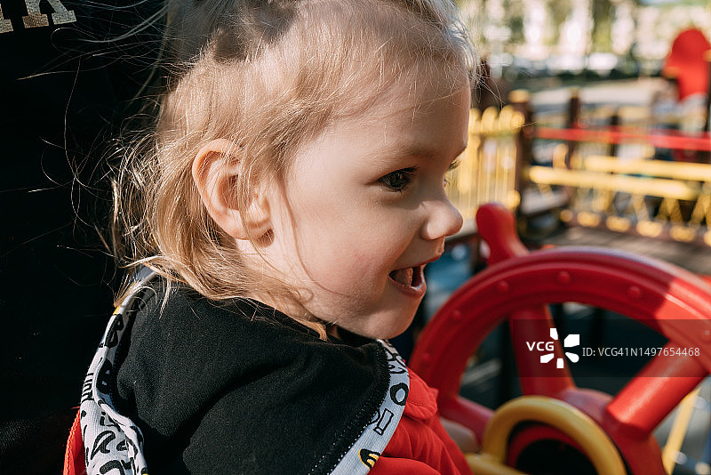 穿着红色雨衣的小女孩在操场上玩耍图片素材