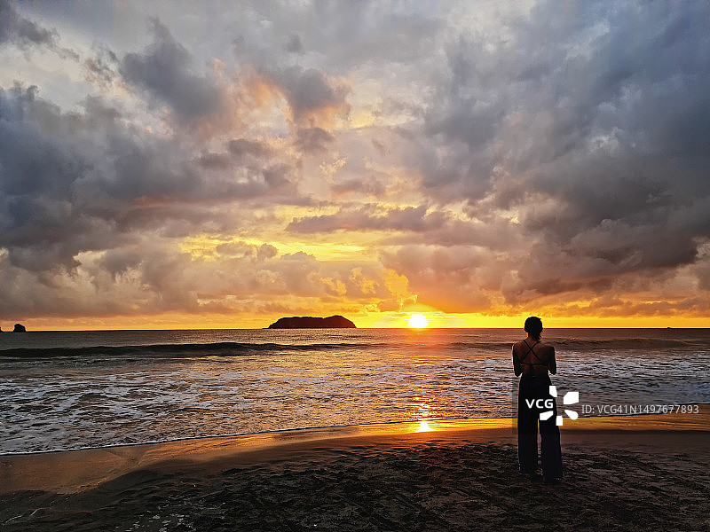 哥斯达黎加热带海滩上，在温暖日落前的年轻女子图片素材