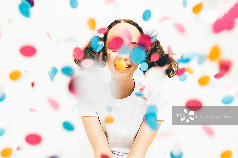 在白色背景下庆祝并撒着五彩纸屑的少女图片素材