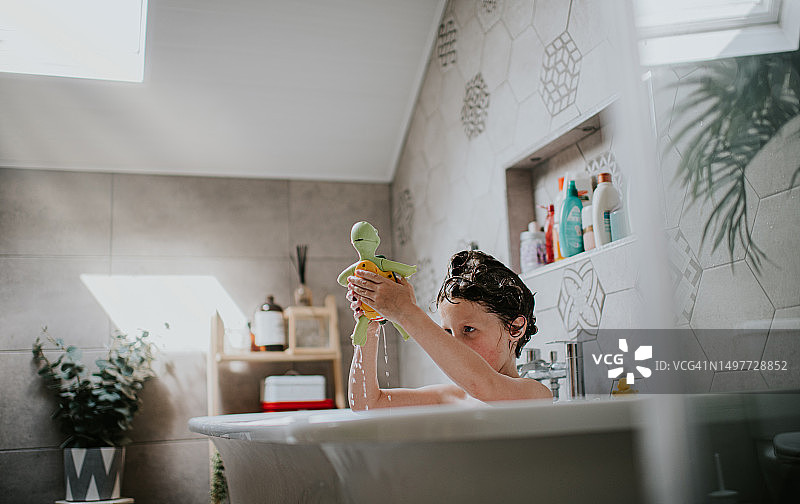 孩子在浴室里玩塑料乌龟浴玩具图片素材