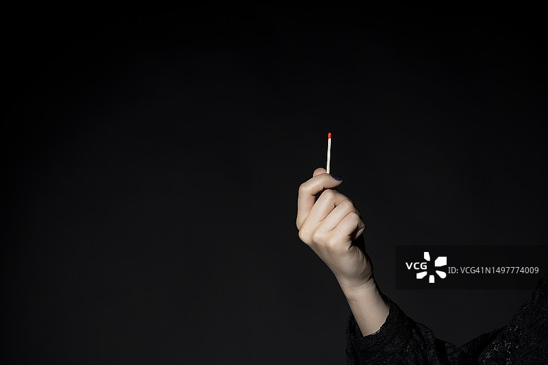 女人手持火柴，黑色背景图片素材