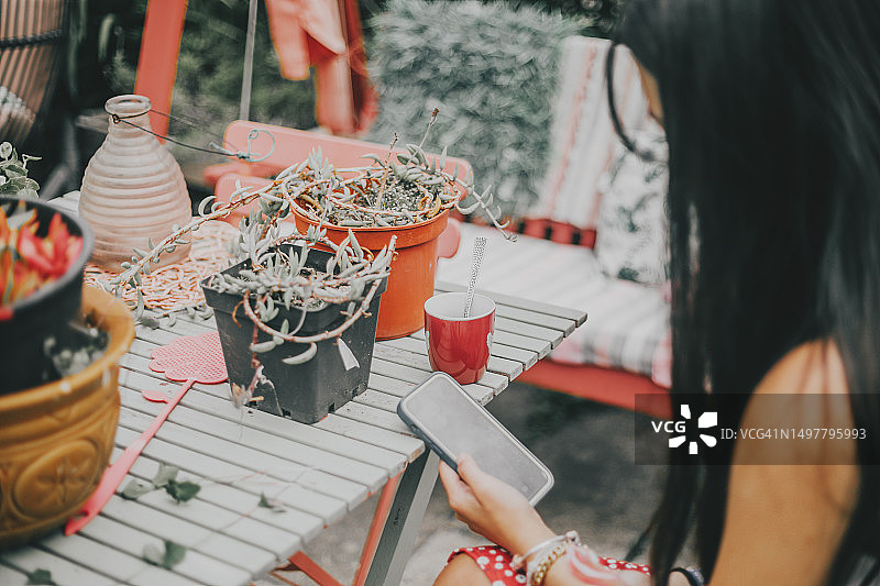 在户外喝咖啡时使用手机的年轻女人图片素材