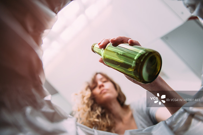 女人将啤酒瓶扔进玻璃回收箱图片素材