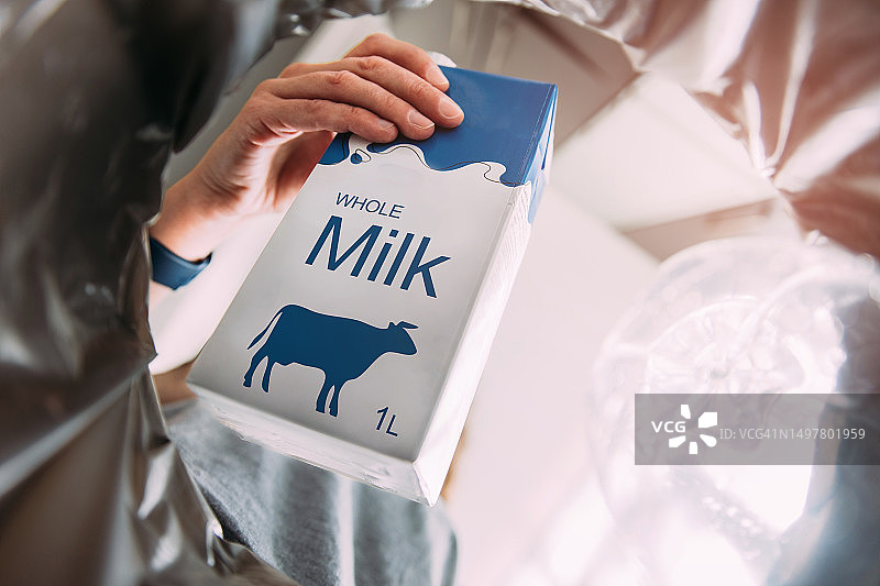 手将牛奶盒扔进塑料回收箱图片素材