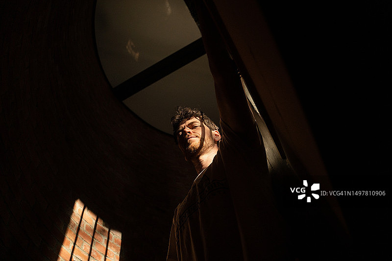 在砖墙背景下，有阴影和阳光的男子肖像图片素材