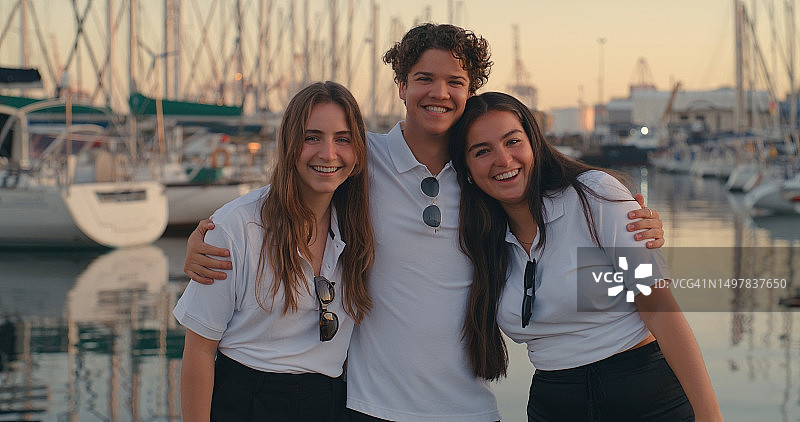 和朋友们在港口一起巡游和度假，在海上旅行、冒险或娱乐。在码头上的年轻人感到高兴或微笑，准备在夏天玩游艇图片素材