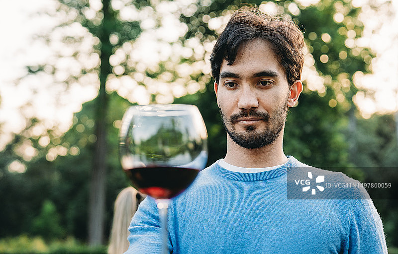 男子在户外日落时品尝红酒图片素材