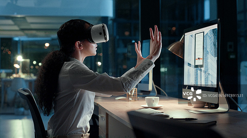 商务实习生佩戴VR头显，在办公室夜晚通过数字用户界面连接并互动。沉浸在人工智能和3D模拟虚拟世界中的女员工图片素材