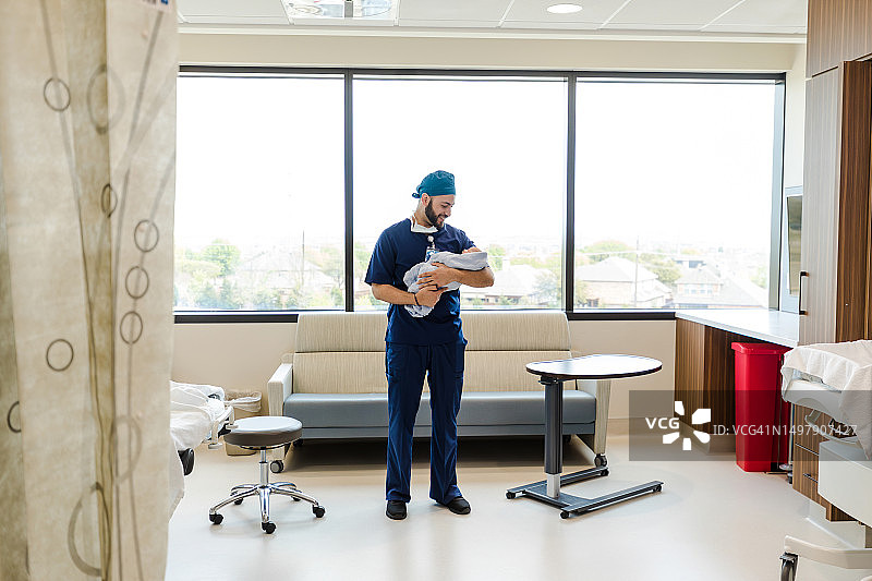 急诊室里，男儿科医生对着婴儿微笑图片素材