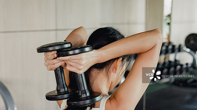 在现代健身房积极锻炼、举哑铃的年轻亚洲健美运动员。运动人士锻炼。图片素材