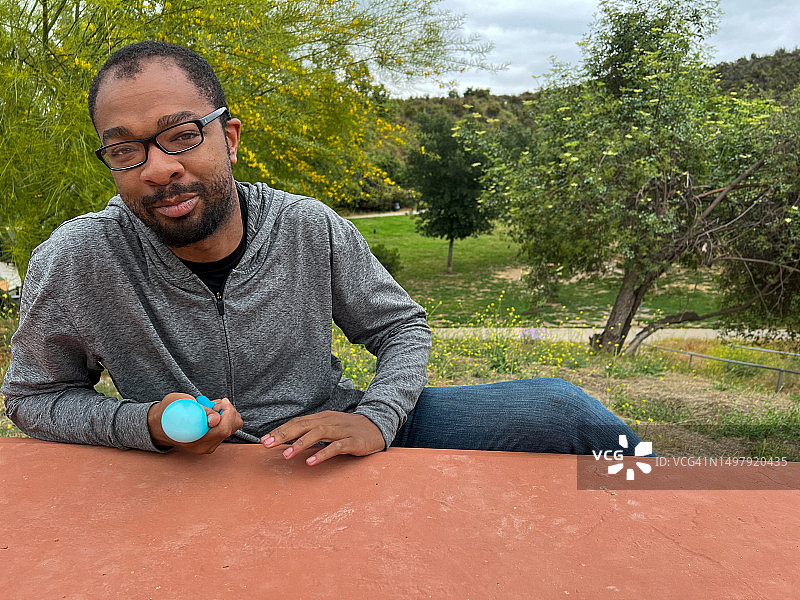 在公园长椅上使用感官玩具的男子肖像图片素材